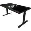 Dual-motor sit/stand adjustable-height gaming desk with built-in PC case, wireless charger, RGB lighting, control panel, and USB ports, tempered glass tabletop, black.