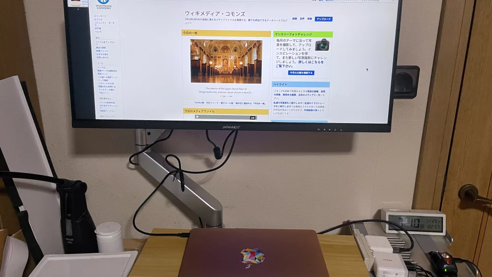 Laptop on a desk next to an ultrawide external monitor on a VESA arm